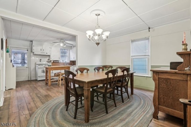 dining room with a wainscoted wall, ceiling fan with notable chandelier, a paneled ceiling, and hardwood / wood-style floors