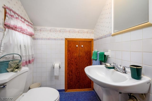 bathroom featuring wallpapered walls, tile walls, and toilet