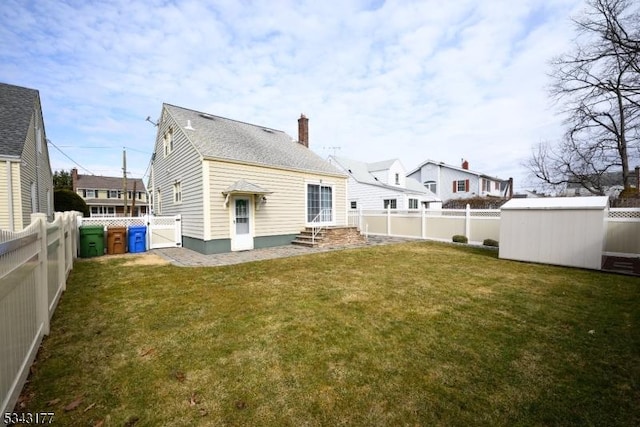 back of house with entry steps, a yard, and a fenced backyard