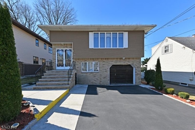 tri-level home with aphalt driveway, entry steps, and a garage