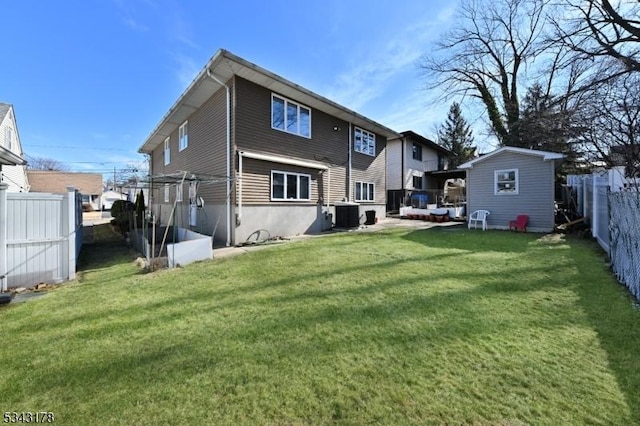 back of house with a yard, central air condition unit, an outbuilding, and a fenced backyard