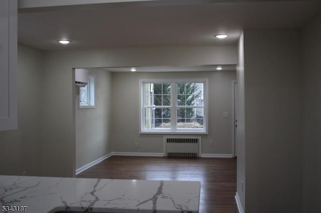 empty room with recessed lighting, baseboards, dark wood-type flooring, and radiator