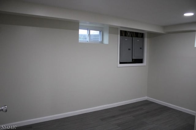 below grade area with electric panel, baseboards, dark wood finished floors, and recessed lighting