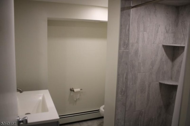 bathroom featuring tile patterned floors, toilet, a tile shower, baseboard heating, and vanity