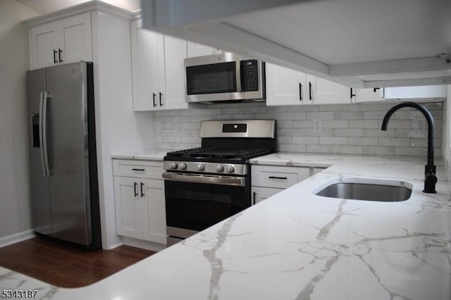 kitchen featuring dark wood finished floors, a sink, white cabinets, appliances with stainless steel finishes, and backsplash