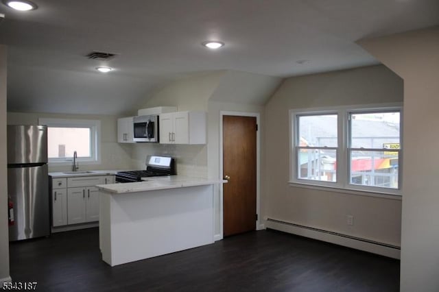 kitchen with a baseboard heating unit, light countertops, appliances with stainless steel finishes, a peninsula, and a sink