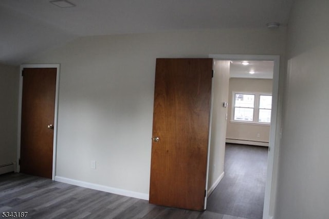 unfurnished bedroom with baseboards, baseboard heating, lofted ceiling, and wood finished floors