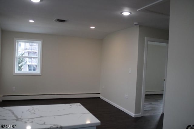 empty room with recessed lighting, a baseboard heating unit, baseboards, and dark wood-type flooring