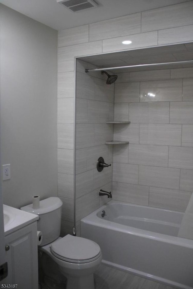 bathroom with visible vents, toilet, shower / bathtub combination, wood finished floors, and vanity