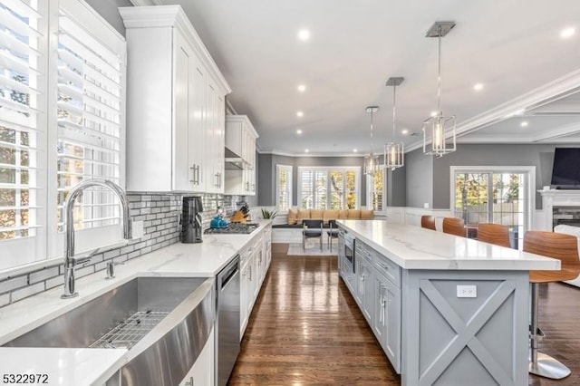 kitchen featuring a sink, appliances with stainless steel finishes, open floor plan, and crown molding