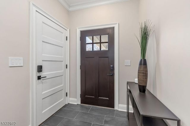 foyer entrance featuring baseboards, dark tile patterned floors, and crown molding