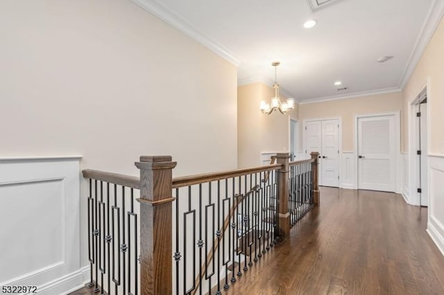 hall featuring an upstairs landing, wood finished floors, an inviting chandelier, wainscoting, and crown molding