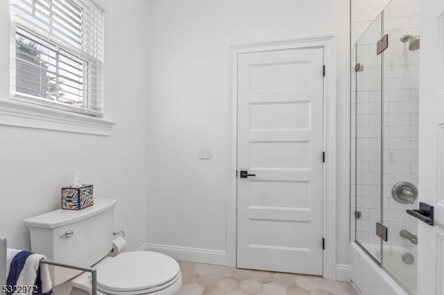 bathroom featuring combined bath / shower with glass door, toilet, and baseboards