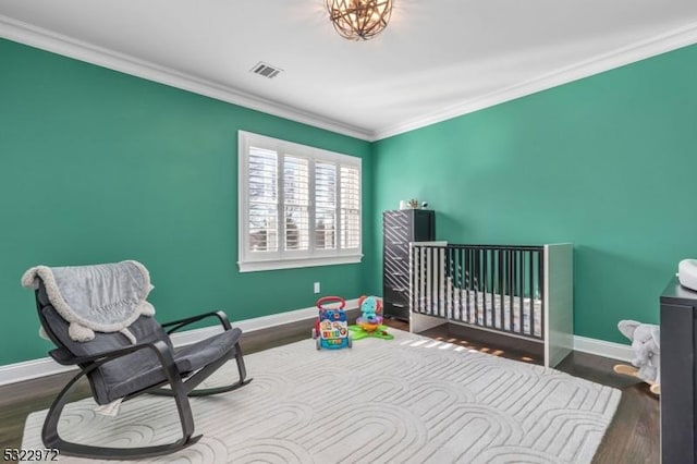 bedroom featuring wood finished floors, visible vents, baseboards, and ornamental molding