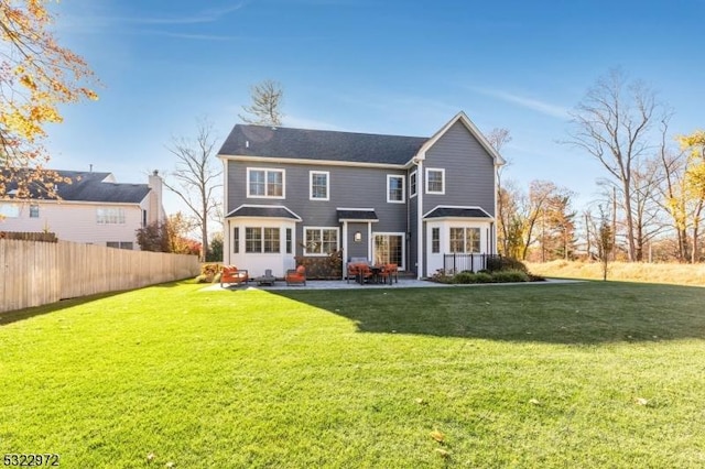 rear view of house with a patio area, a yard, and fence