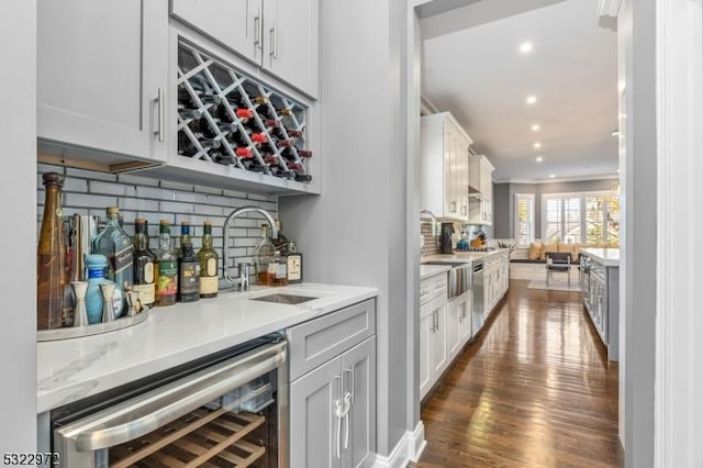 bar featuring dark wood-style flooring, a sink, indoor wet bar, decorative backsplash, and wine cooler