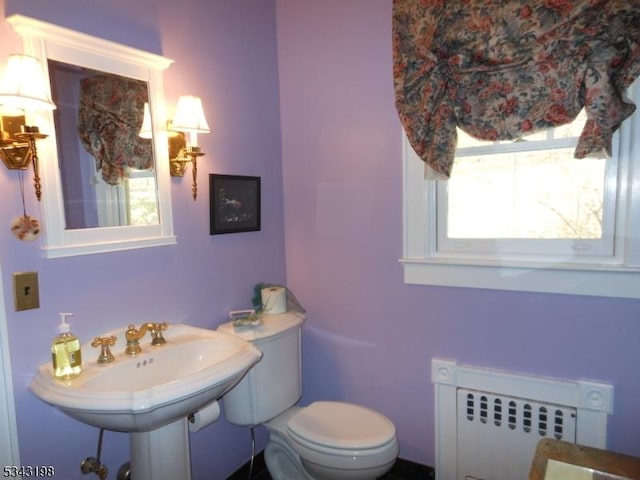 half bath featuring toilet, radiator, a wealth of natural light, and a sink