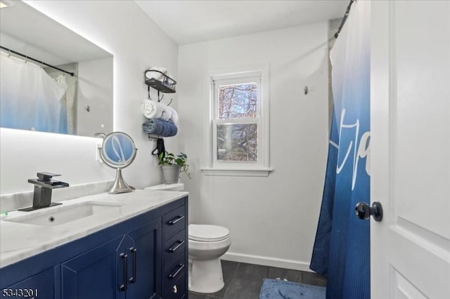 bathroom with vanity, toilet, wood finished floors, and baseboards