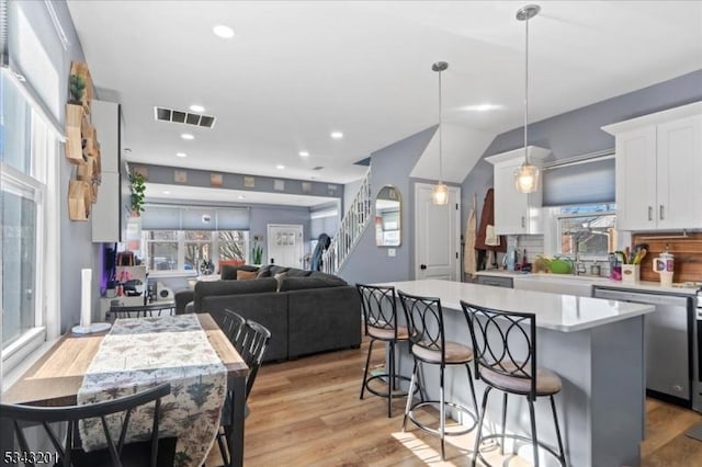 kitchen with visible vents, a sink, stainless steel dishwasher, white cabinets, and light countertops