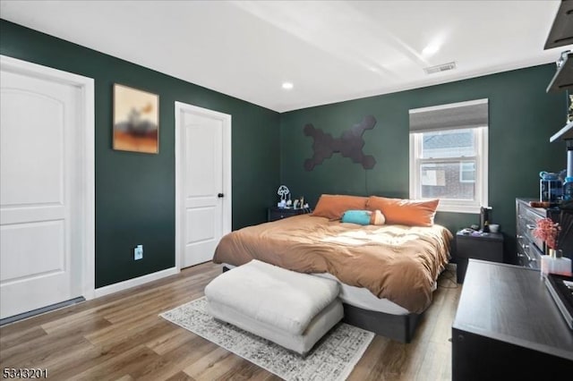 bedroom featuring visible vents, baseboards, and wood finished floors