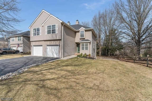 view of front facade featuring a front yard, fence, driveway, a chimney, and a garage