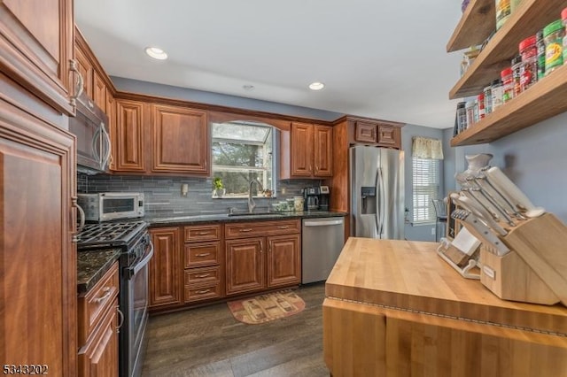 kitchen featuring dark wood-type flooring, a sink, stainless steel appliances, decorative backsplash, and wooden counters