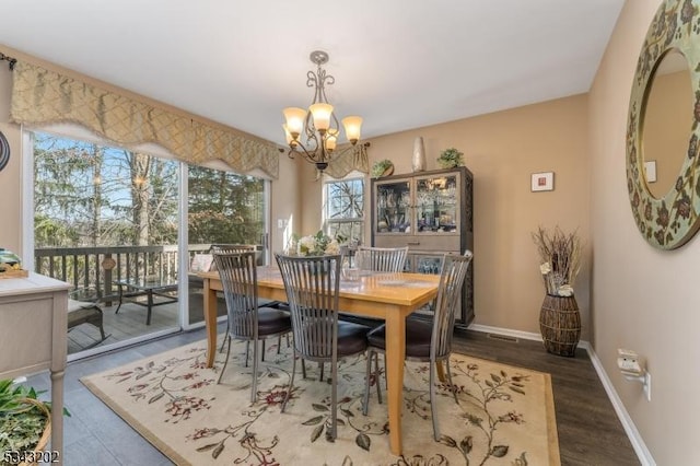 dining area with baseboards, wood finished floors, and a chandelier