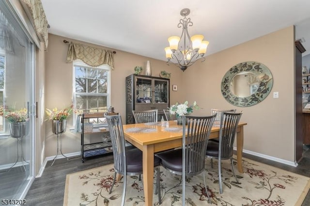 dining room with a notable chandelier, baseboards, and wood finished floors