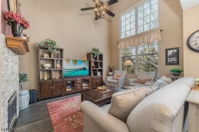 living area featuring ceiling fan, wood finished floors, and a towering ceiling