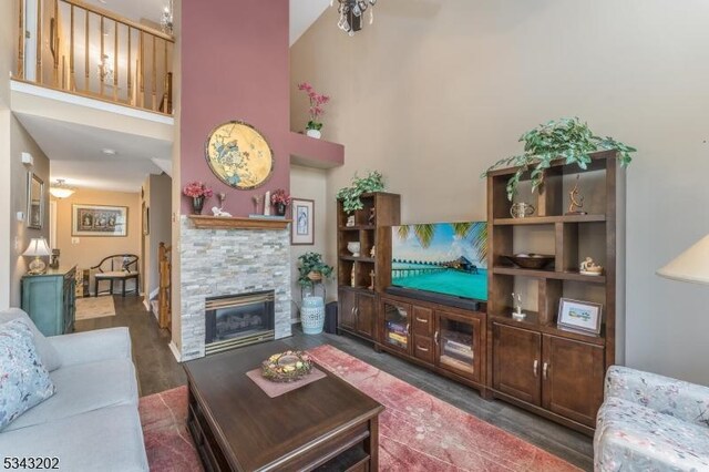 living area featuring a stone fireplace and a towering ceiling