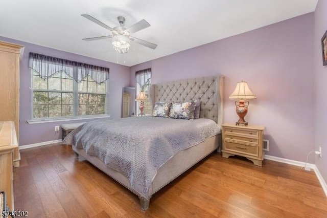 bedroom with a ceiling fan, wood finished floors, and baseboards