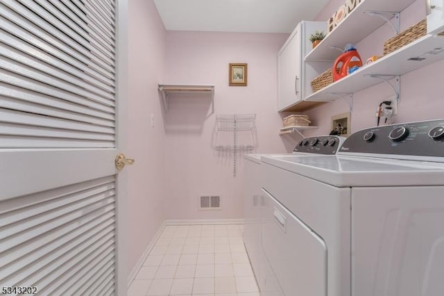 laundry area featuring washer and clothes dryer, visible vents, cabinet space, and light tile patterned floors