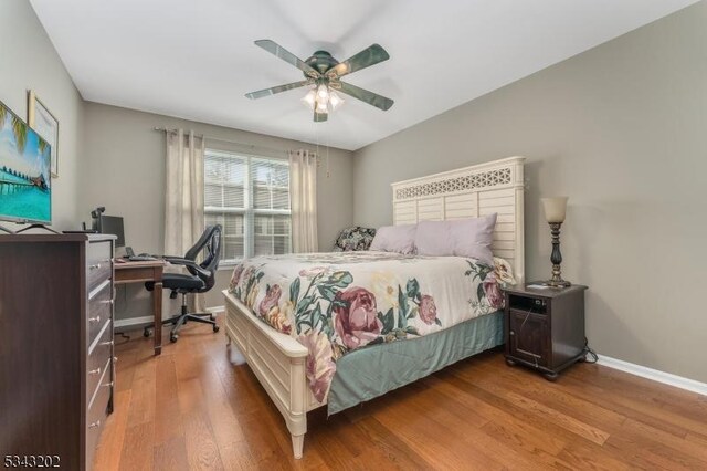 bedroom with a ceiling fan, baseboards, and wood finished floors