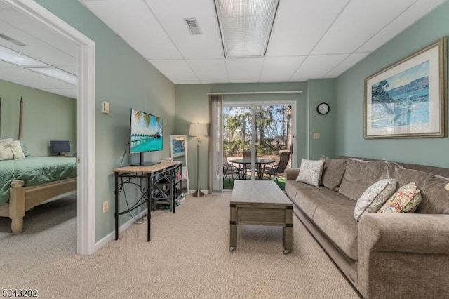 living area with visible vents, a drop ceiling, baseboards, and carpet floors