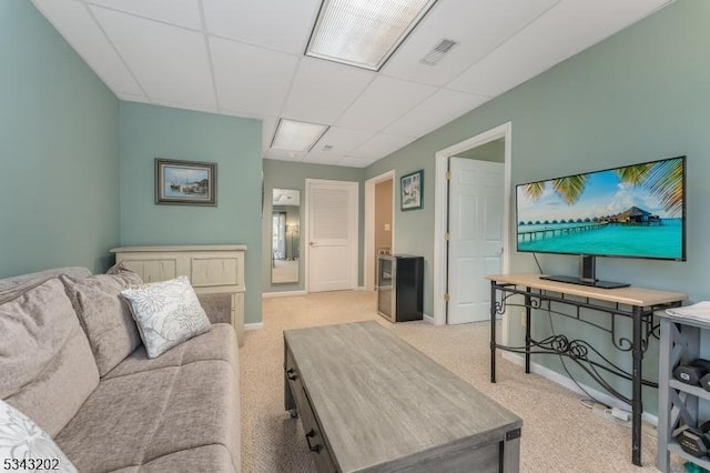 carpeted living room featuring a paneled ceiling, visible vents, and baseboards