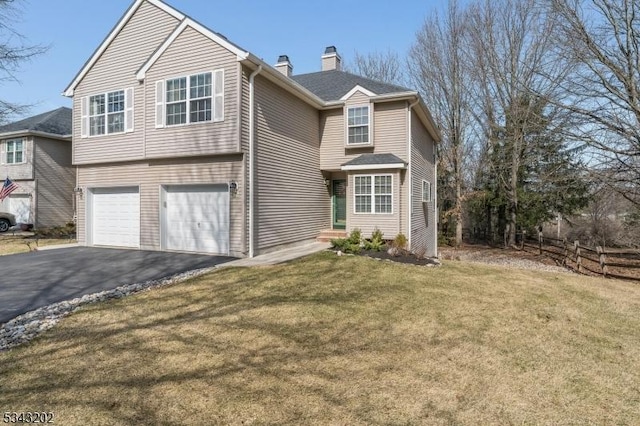 view of front of house with an attached garage, fence, a front yard, a chimney, and driveway