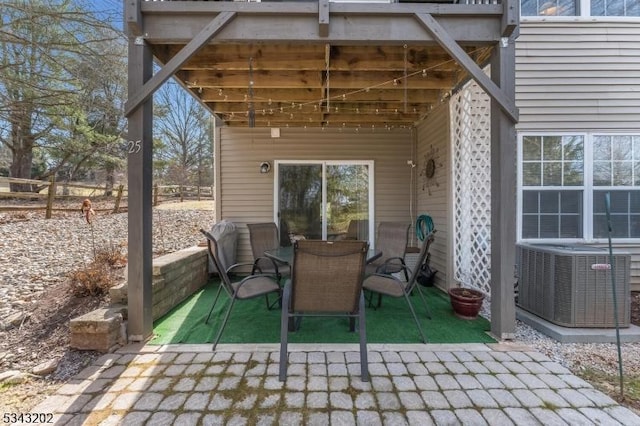 view of patio with outdoor dining space, central AC, and fence