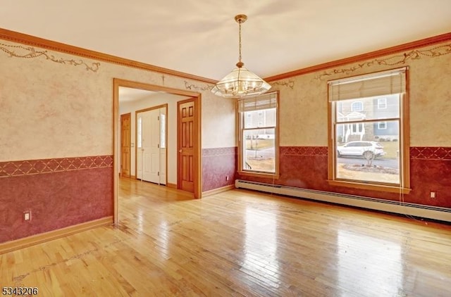 spare room featuring a baseboard radiator, an inviting chandelier, wainscoting, crown molding, and light wood-type flooring