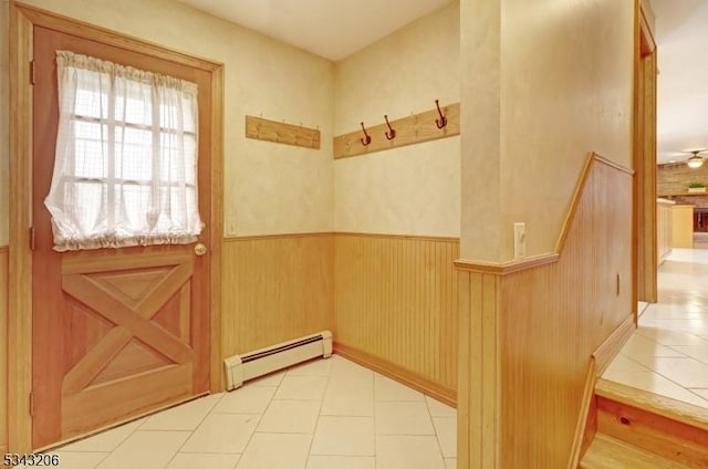 entryway with light tile patterned floors, a baseboard heating unit, wood walls, and wainscoting