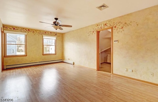 spare room with baseboard heating, a ceiling fan, visible vents, and wood finished floors