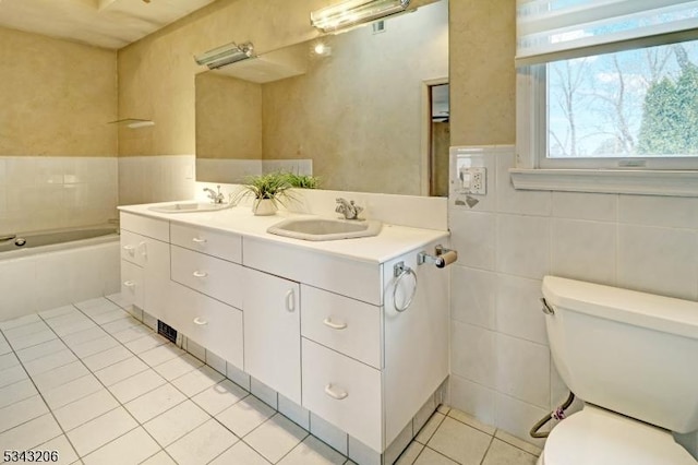 bathroom featuring tile patterned flooring, toilet, tile walls, and a sink