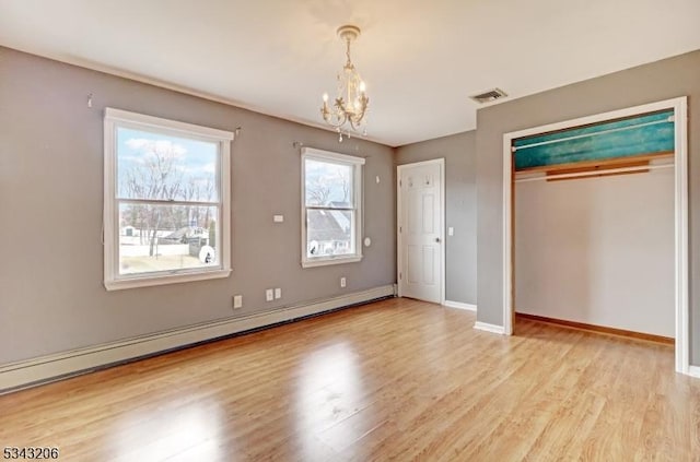 unfurnished bedroom with visible vents, a baseboard heating unit, baseboards, a chandelier, and light wood-style floors