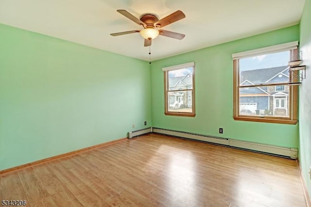 spare room with a baseboard heating unit, wood finished floors, baseboards, and a ceiling fan