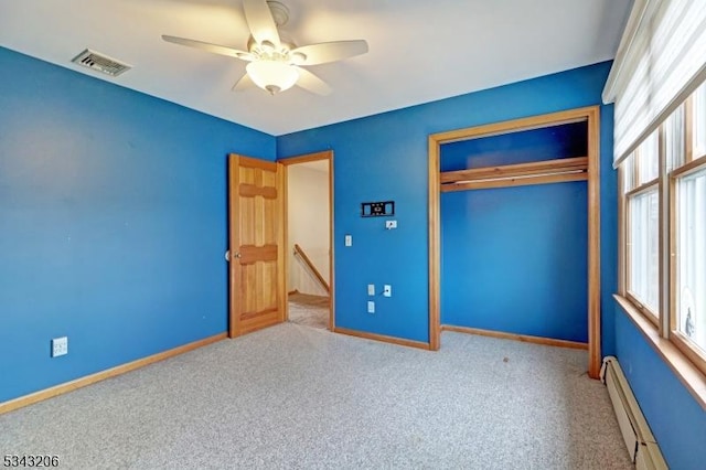 unfurnished bedroom featuring visible vents, a baseboard heating unit, baseboards, carpet floors, and a closet