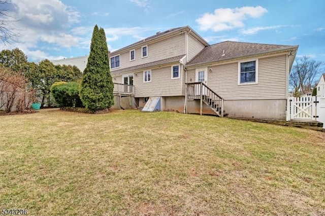 rear view of house with a gate, a lawn, and fence