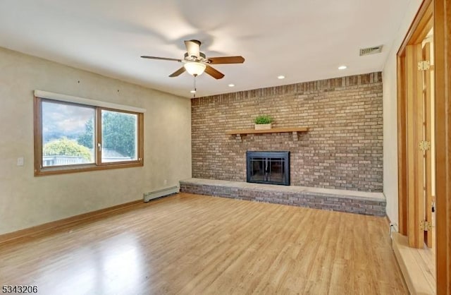 unfurnished living room with visible vents, a baseboard heating unit, ceiling fan, a fireplace, and wood finished floors