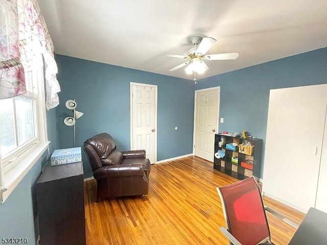 sitting room featuring baseboards, a ceiling fan, and wood finished floors