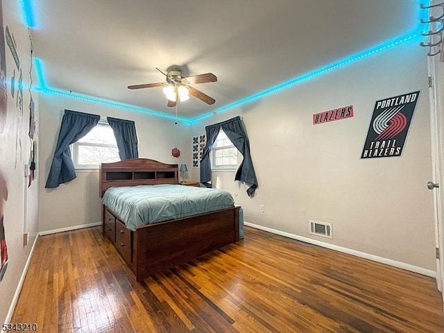 bedroom with multiple windows, wood finished floors, visible vents, and baseboards