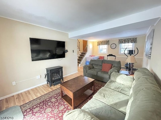 living room featuring wood finished floors, stairway, crown molding, baseboards, and a wood stove