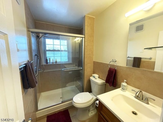 bathroom with visible vents, toilet, tile walls, a shower stall, and vanity